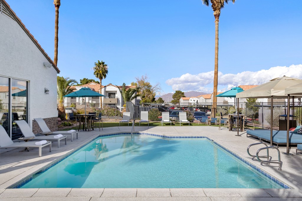 a swimming pool with lounge chairs and umbrellas at the enclave at woodbridge apartments in